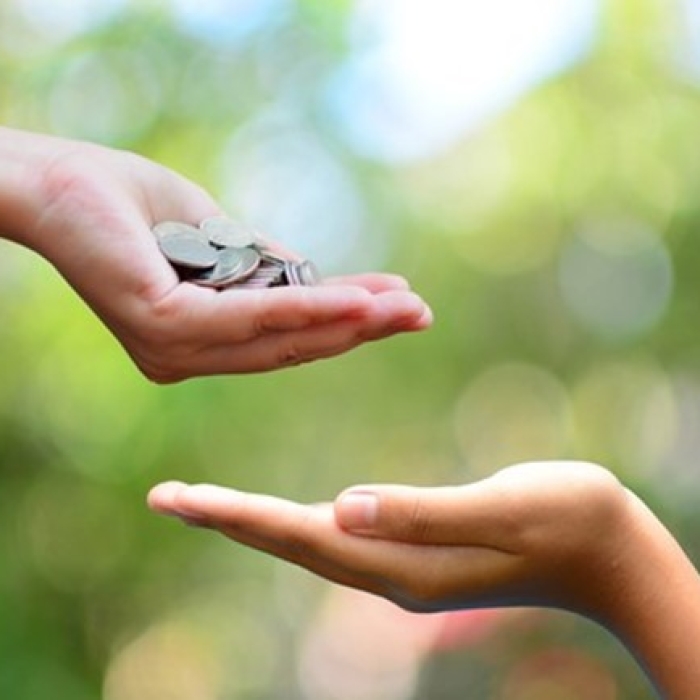 A person's hands holding coins above another open hand