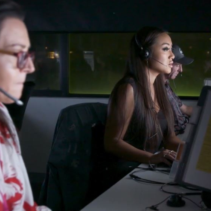 Three Lifeline crisis supporters, two women and one man, are focused at their computer screens, wearing headsets in a dimly lit support center. This image conveys the dedication of Lifeline staff working diligently, often outside of traditional hours, to answer calls and provide vital support to those in need.