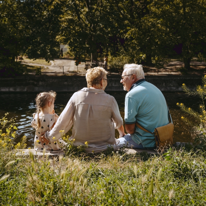 Senior couple sitting at lake with a child