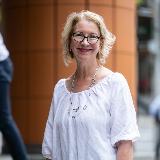 Imbi Pyman, wearing a white blouse, standing on the steps of an office building in Sydney CBD